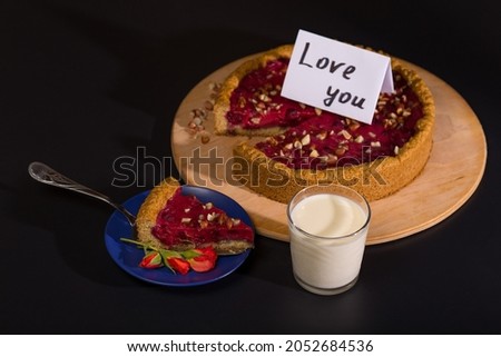 Baking sweet pie with fruits for Valentine and prepared on a plate with little flowers, on black background.