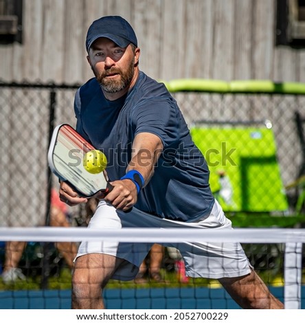 Male pickelball player reaches for the ball during a tournament Royalty-Free Stock Photo #2052700229