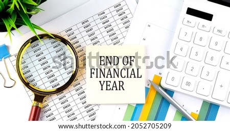 END OF FINANCIAL YEAR text on sticker on diagram with magnifier and calculator. Business