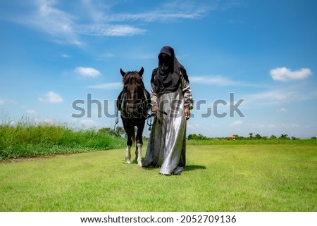 Portrait of Muslim women and horse in the meadow