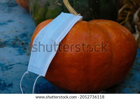 Blue medical mask on an orange pumpkin. No holiday concept. Gloomy photo.