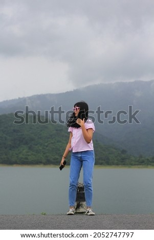 A Women were sunglass standing with mountain and clouds background 
