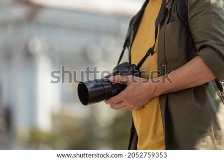 Cropped portrait of man, photographer, cameraman with professional camera, equipment during working summer day outdoors. Concept of occupation, job, education, caree and hobby