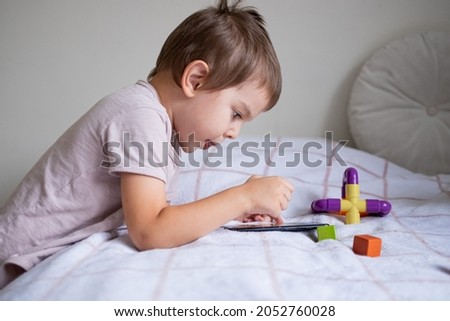 Little preschool boy playing via smartphone at home. High quality photo