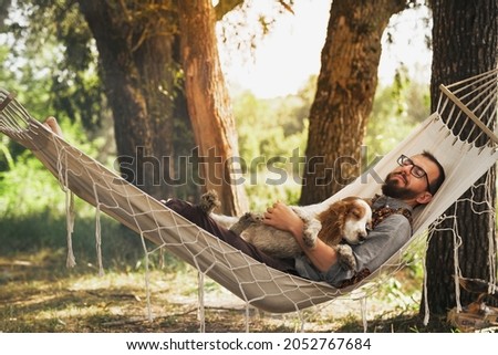 Person sleeping with his dog in a hammock in beautiful summer scene Royalty-Free Stock Photo #2052767684