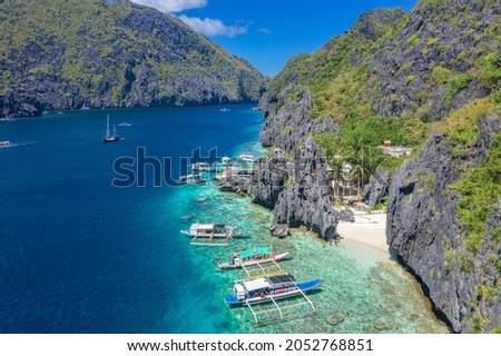 Beautiful coral reef, boats and a clear ocean on Matinloc Island, Bacuit Archipelago, El Nido, Palawan, Philippines. Aerial drone view. Royalty-Free Stock Photo #2052768851