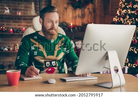 Photo of charming young serious focused man sit desk computer write notebook job indoors inside house home