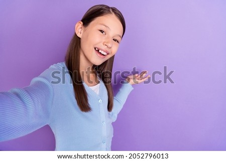 Photo of sweet brunette little girl do selfie hold empty space wear blue shirt isolated on violet color background