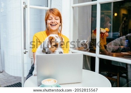 Lovely pet concept. Happy excited woman student laughing watching movie, working with laptop hugging cute dog. Relax, carefree, comfort lifestyle concept.