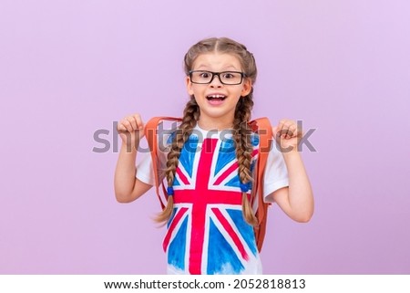 A little girl in a T-shirt with an image of the English flag on an isolated purple background. Learning foreign languages.