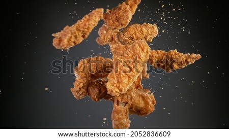 Freeze motion shot of flying tasty fried chicken wings or strips Royalty-Free Stock Photo #2052836609