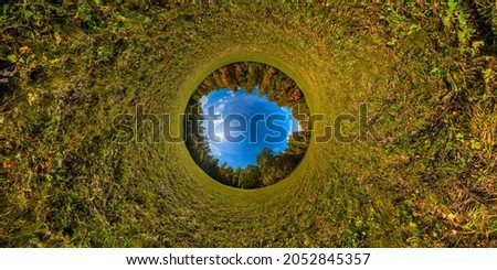 hyperbolic tunnel projection of 360 by 180 degree spherical panorama of sunny autumnal mowed meadow and yellow forest with blue sky and clouds.