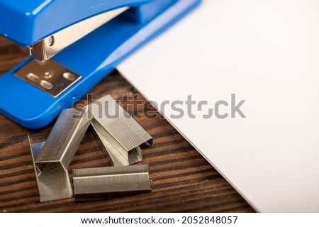 Office stapler, stapler staples and white paper on the table, close-up, selective focus