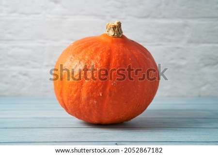 Isolated hokkaido pumpkin on a blue wooden table.                               