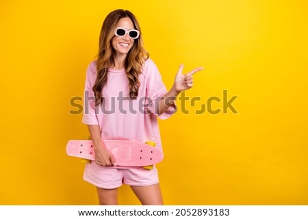 Photo of young woman happy positive smile longboard point finger empty space ad choice isolated over yellow color background