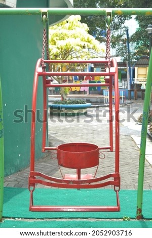 a swing chair in a red garden in the photo from one side of a park that looks deserted in a recreation center in Yogyakarta during the covid 19 pandemic