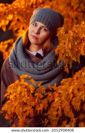 Portrait of a beautiful lady surrounded by autumn leaves. Walk through the autumn park. October portrait. Park with yellow leaves. Autumn atmosphere. Vintage photo. Selective focus.