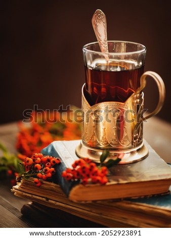 Autumn still life with tea and books. Cozy home. Autumn leaves, book and cup of tea on wooden table.