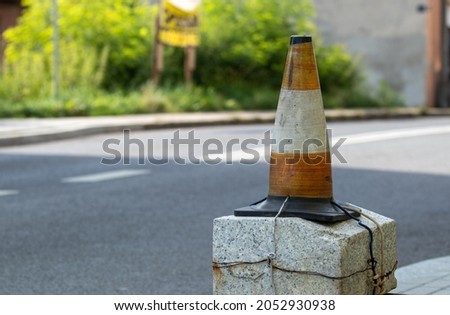 a bollard in orange and white, pinned to a stone pole