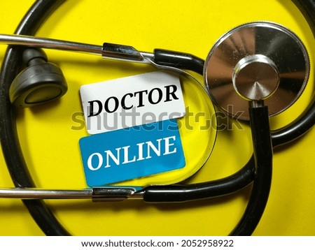 Stethoscope and ear bud with colored wooden board written with text DOCTOR ONLINE on a yellow background.