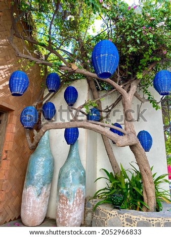 Blue Basket Lanterns in a scenic setting in Cabo San Lucas, Mexico. Tall pottery vases, brick walls and greenery. A beautiful corner of town.