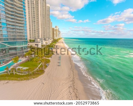 Beautiful drone view of Sunny Isles Beach looking North on a sunny morning with minimal shadows displaying white sandy beach and turquoise blue water