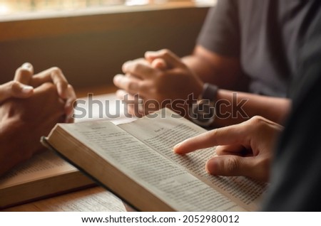 young man reading bible with friends who are praying to God Join the cell group at the church. A small group of Christians or concepts in a church at a church. Royalty-Free Stock Photo #2052980012