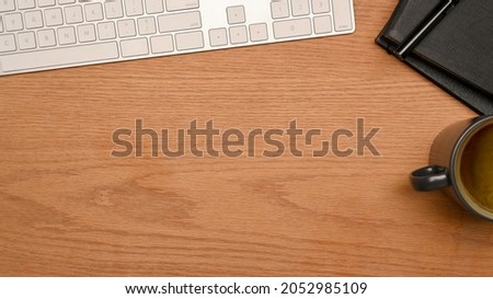 Top view of Simple workspace with keyboard, notebook, coffee cup and space for montage on wooden table. wooden background