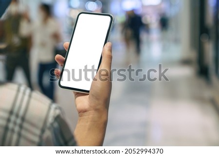 close up on hand holding phone showing white screen display walking in supermarket department store