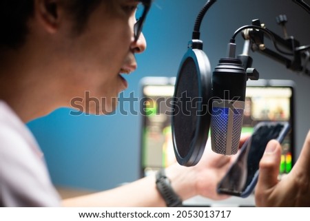 Asian influencers using microphone for podcasts and record sound for upload file to system.Live recording .Speaking online with mobile.Studio audio broadcast.