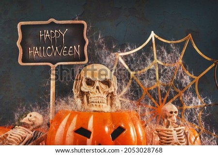 Halloween party set up props. Three skeletons having a spooky party with pumpkin and spider and a lollipop. Dia de los Muertos and Halloween. Dark themed copy space. trick or treat
