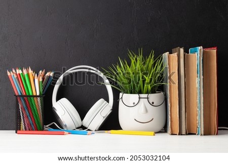 Table with books and plant with glasses and headphones. Work and education concept. With copy space