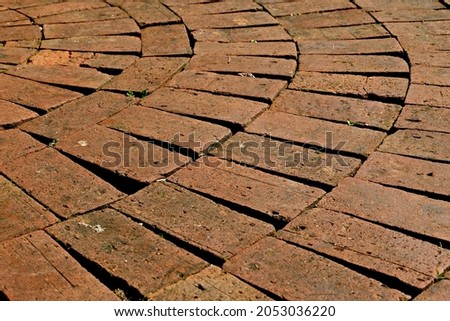 Close-up of brick pavement lying in circle platform, Pattern of walkway in the garden, Circle shape pavement filled with red bricks, Brick surface plaza in a circular pattern in the garden