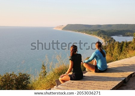 Tourists enjoying beautiful sunset scenery at the Empire Bluff Scenic Lookout, overlooking Lake Michigan, the Sleeping Bear Dunes, and the Manitou Island Royalty-Free Stock Photo #2053036271