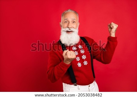 Photo of funny lucky mature man dressed print sweater smiling rising fists empty space isolated red color background