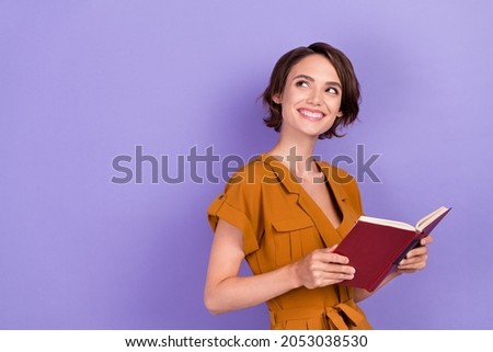 Photo of happy dreamy joyful young woman hold hands book reader look empty space isolated on purple color background