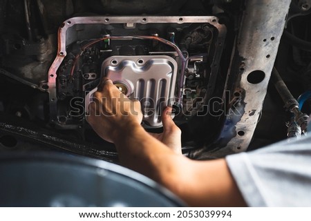 Auto mechanic installing an automatic transmission filter.  Royalty-Free Stock Photo #2053039994