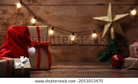 Christmas composition. Santa hat and Christmas gift boxes on wooden table.