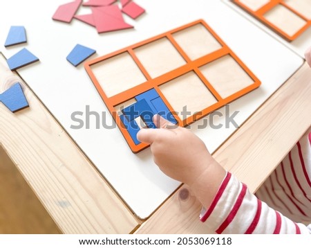 The child collects puzzles. Educational wooden toy for learning. Montessori materials. Fine motor skills, hand-eye coordination. Children's leisure, nursery.The concept of early development. squares. 