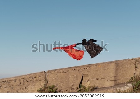 red and black raincoat fly, hold hand. High quality photo