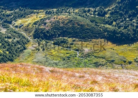 Hillside and valley with a mountain stream against the backdrop of blue mountain peaks Royalty-Free Stock Photo #2053087355