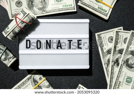 Lightbox board with word DONATE in black letters around US dollar banknotes. Money, Business, finance, investment, saving. Cash bill. Business budget of wealth and prosperity finance