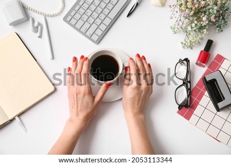 Woman with beautiful manicure holding cup of coffee on white table