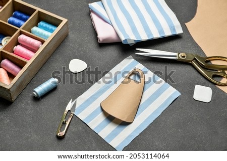 Tailor's supplies with pattern of medical mask on dark background