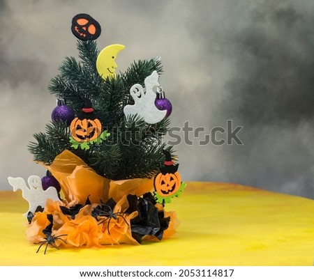 Halloween composition, halloween christmas tree decorated with silhouettes of bat, pumpkin and ghosts.  Googly eyes