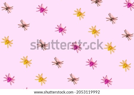 Colorful pattern of spiders on pastel pink background. Minimal creative Halloween idea.