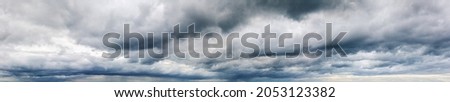 Stormy cloudy sky wide panorama, dramatic dark blue thunderclouds, gale cloudscape, gray cumulus rain clouds panoramic view, thunderstorm heaven landscape, overcast cloudiness weather, hurricane skies Royalty-Free Stock Photo #2053123382