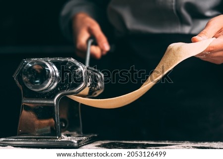 Close up dark photo of the pasta making machine in process. Royalty-Free Stock Photo #2053126499