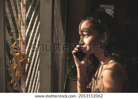 A young woman begins to cry and be overcome with emotions while realizing the bad news told to her via the phone. Royalty-Free Stock Photo #2053152062