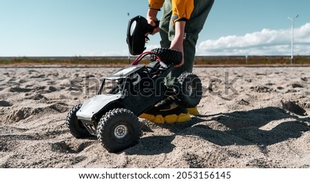 Male kid hands holding radio controlled wireless drive high speed sport car toy and joystick Royalty-Free Stock Photo #2053156145